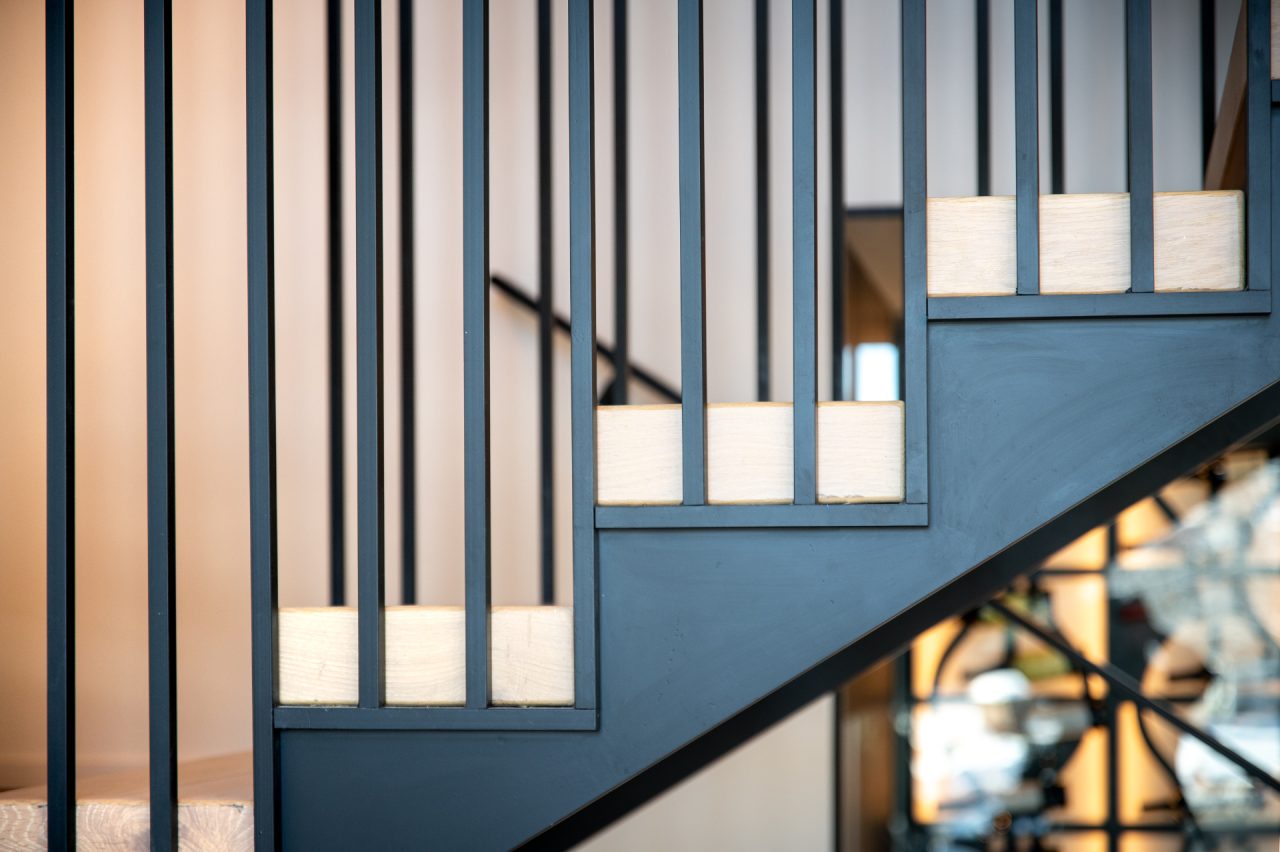 Modern staircase with metal railings and wooden steps.